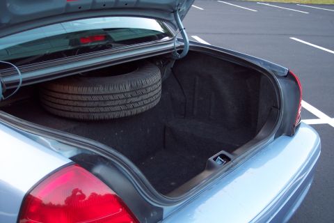 2001 Ford Crown Victoria - The open trunk of a light blue 2001 Ford Crown Victoria reveals a spare tire and the car's interior.