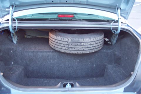 2001 Ford Crown Victoria - The trunk of a vehicle, showing the spare tire and jack, with the lid open.
