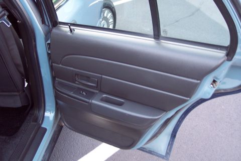 2001 Ford Crown Victoria - The interior door panel of a 2001 Ford Crown Victoria is visible, with a glimpse of the exterior and another vehicle through the window.