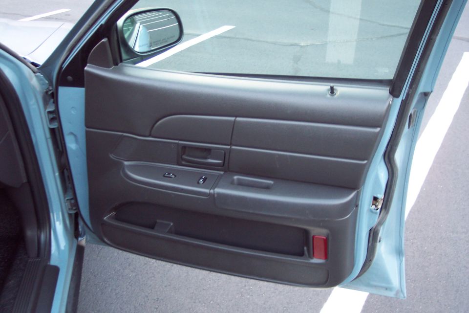 Interior of a car door, showing the panel, window controls, and door handle