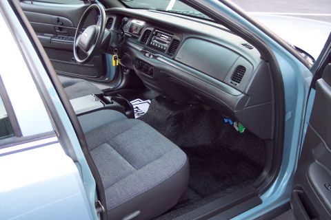2001 Ford Crown Victoria - The interior of a police-style sedan is shown, cloth seats and a standard dashboard layout.