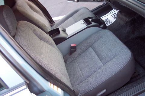 2001 Ford Crown Victoria - The interior of a car shows grey fabric seats and a floor mat with text.