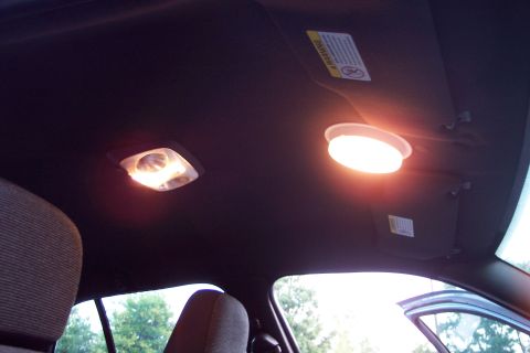 2001 Ford Crown Victoria - The interior of a vehicle shows two illuminated dome lights and a warning label on the sun visor.