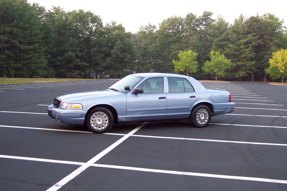 Light blue 2001 Ford Crown Victoria sedan, side view, parked in an empty lot