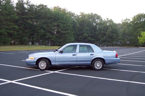 2001 Ford Crown Victoria - Side profile of a light blue 2001 Ford Crown Victoria sedan in a parking lot.