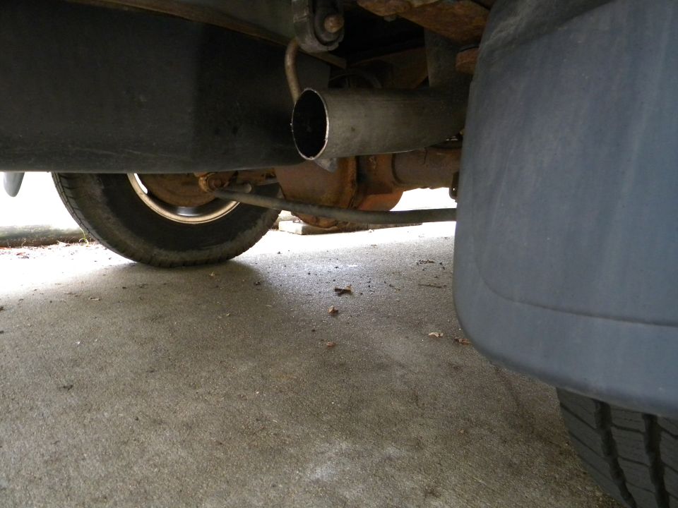 Underside view of a vehicle's exhaust pipe, rear axle, and tire
