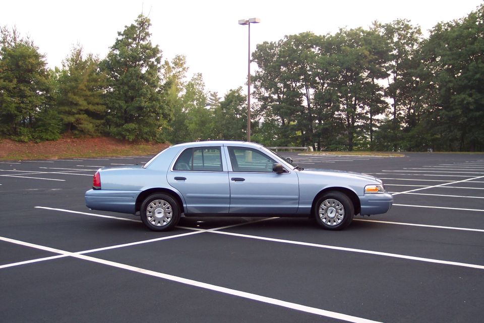 Light blue 2001 Ford Crown Victoria sedan parked in an empty lot, side view