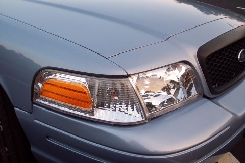 2001 Ford Crown Victoria - The front corner of a light blue sedan is captured in this close-up shot, highlighting the headlight assembly and part of the grille.