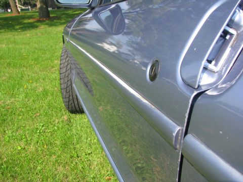 1994 Ford Probe - Close-up of the side of a 1994 Ford Probe, showing the door and a tire.
