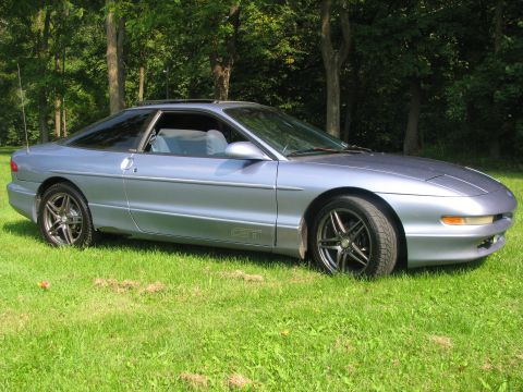 1994 Ford Probe - 1994 Ford Probe GT with aftermarket wheels parked on a grassy area with trees behind it.