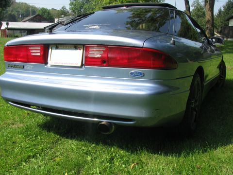 1994 Ford Probe - The rear of a light blue 1994 Ford Probe GT is visible, parked on a grassy area.