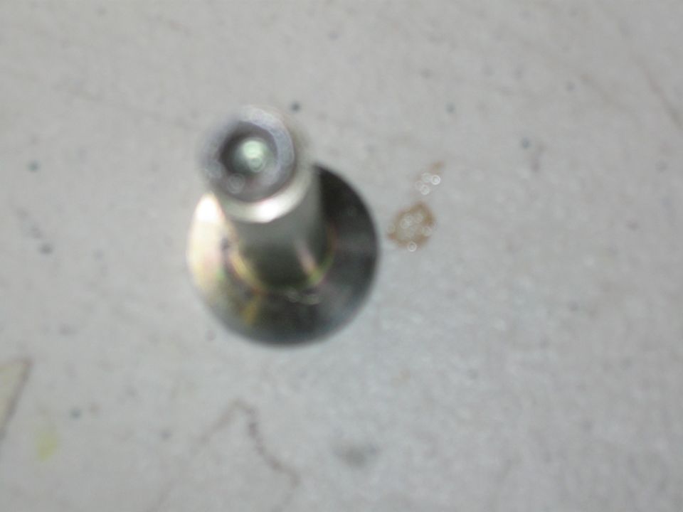 Metal bolt with a washer, on a light gray surface. Text "SUPERMOTORS www.supermotors.net" is visible in the lower right