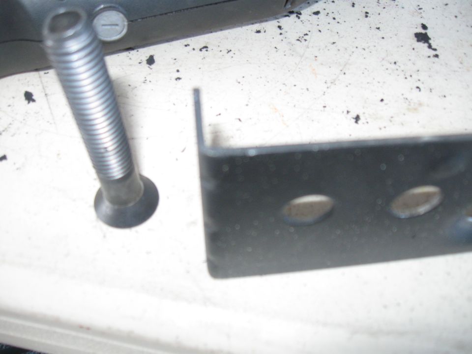 Close-up of a bolt and a black metal bracket with two holes