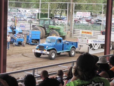 1989 Ford Bronco - A blue 1945 Dodge Power Wagon pickup truck is seen at an outdoor event with other vehicles and spectators.