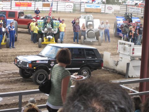 1989 Ford Bronco - A black Range Rover SUV is seen on a dirt track with other vehicles and spectators in the background.