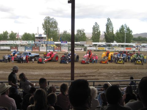 1989 Ford Bronco - Spectators watch a tractor pull competition modified tractors and trucks on a dusty track under a cloudy sky.