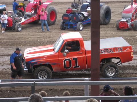 1989 Ford Bronco - An orange pickup truck, painted to resemble the General Lee from Dukes of Hazzard, is shown at an event with other vehicles.