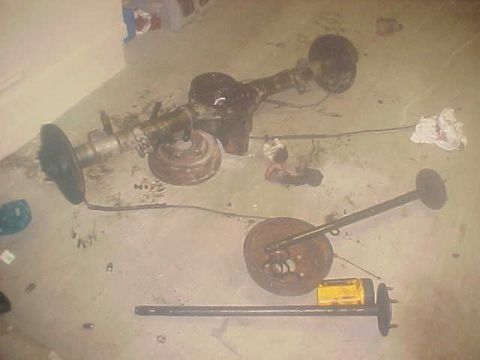 1996 Ford Bronco - Vehicle axle and brake parts are disassembled and spread across the floor.