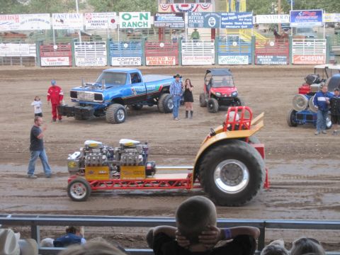 1989 Ford Bronco - Competitors and spectators gather at a tractor pull event modified vehicles on a dirt track.
