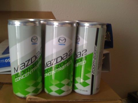 1990 Ford Probe - Three cans of Mazda Zoom-Zoom Concentrated are arranged on a surface.