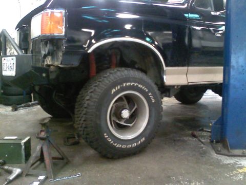 1990 Ford Bronco - A black Ford Bronco with tan trim is shown in a garage, possibly undergoing modifications.