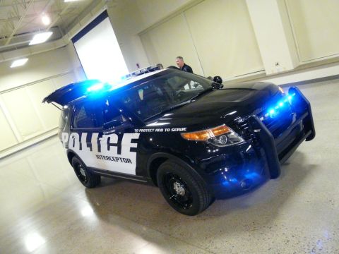1993 Ford Taurus - Police SUV with "To Protect and To Serve" text on the side, illuminated by emergency lights.