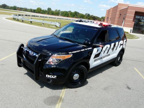 1993 Ford Taurus - A police interceptor SUV is parked on asphalt with a building and trees in the background.