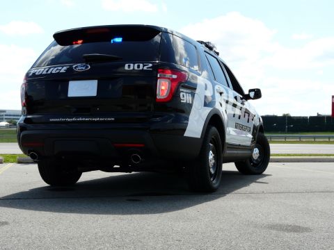 1993 Ford Taurus - A black Ford Police Interceptor Utility SUV is parked in a lot, displaying police markings and emergency lights.