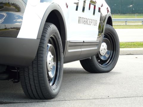 1993 Ford Taurus - A white and black police utility vehicle is shown from the side, with a focus on its wheels and the "INTERCEPTOR" text on the door.