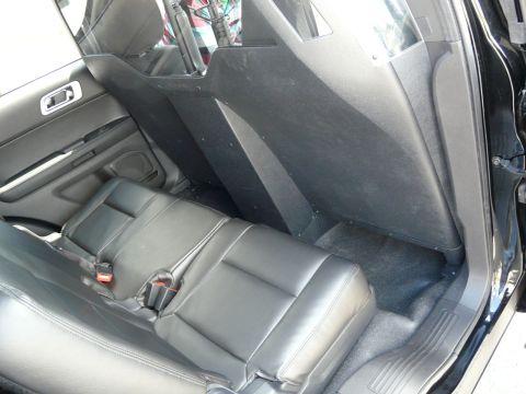 1993 Ford Taurus - Rear interior of a police vehicle, showing the back seats and the partition separating the front and rear compartments.
