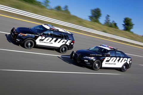 1993 Ford Taurus - Two police interceptor vehicles, a Ford Explorer SUV and a Ford Taurus sedan, are captured in motion on a race track.