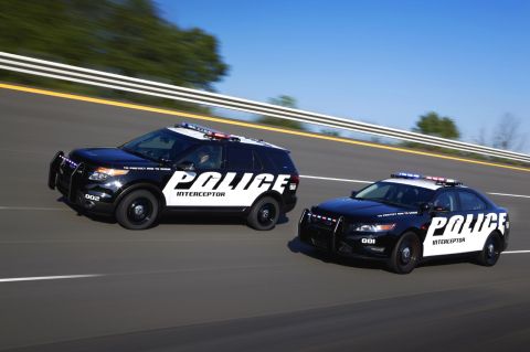 1993 Ford Taurus - Two Ford Police Interceptor vehicles, a sedan and an SUV, are captured in motion on a highway.