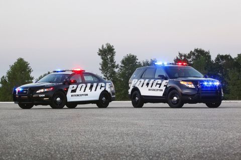 1993 Ford Taurus - Two Ford Police Interceptor vehicles, a sedan and an SUV, are parked side-by-side on asphalt.