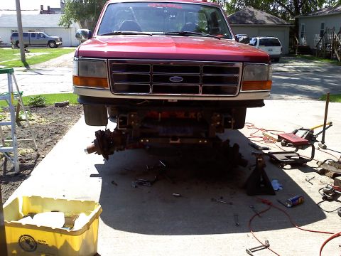 1996 Ford F-150 - Front end of a 1996 Ford F-150 undergoing suspension work, with parts scattered around.