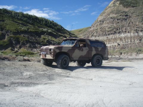 1985 Ford Bronco - Ford Bronco with camouflage paint scheme parked in a dry, hilly terrain under a blue sky.