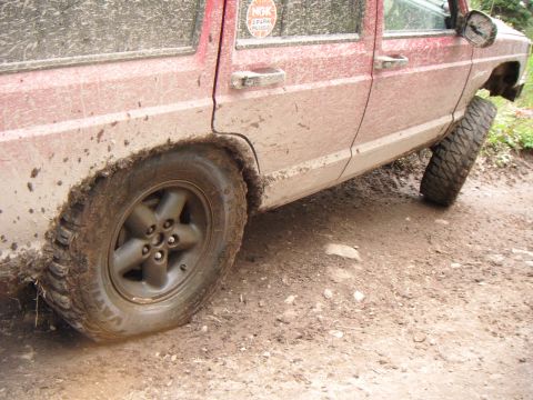 1998 Jeep Cherokee - This red Jeep Cherokee is covered in mud while driving on a dirt road.