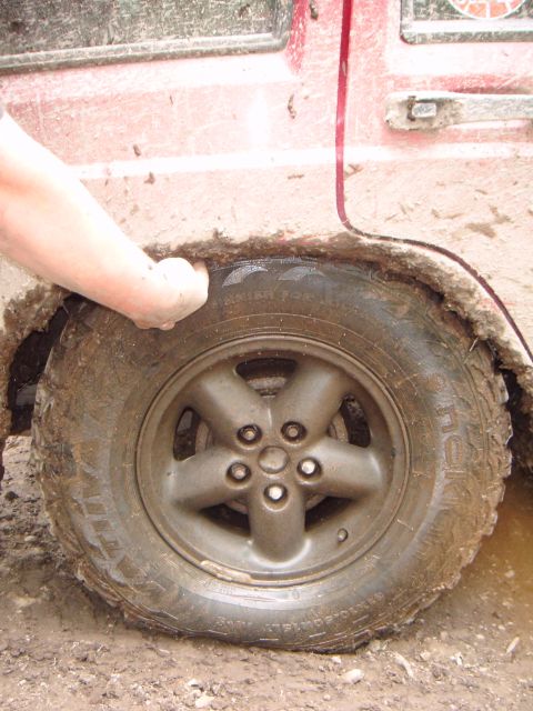 1998 Jeep Cherokee - A red SUV is stuck in the mud, with its tire partially submerged in the mire.