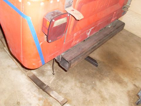1985 Jeep CJ7 - The rear of a red Jeep CJ shows a custom bumper installation and bodywork with blue tape.