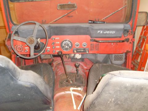 1985 Jeep CJ7 - Interior view of a red Jeep CJ showing the dashboard, steering wheel, and seats.