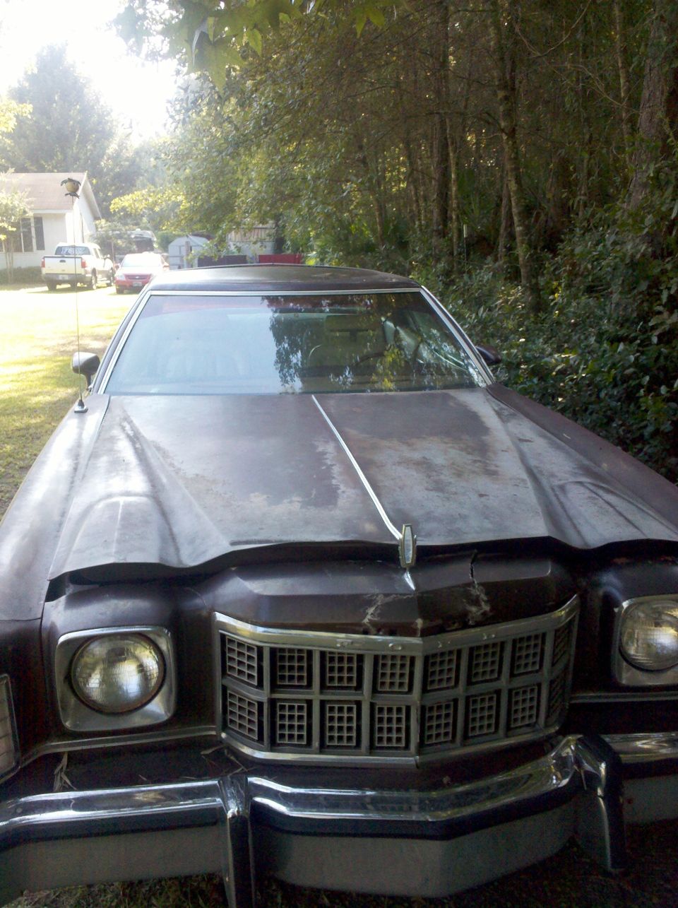 Faded maroon 1970s Ford coupe, front view showing egg-crate grille and quad round headlights
