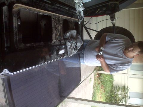 1995 Ford Bronco - A person is seen working on the interior of a vehicle's tailgate, with the window removed.