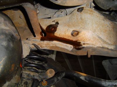 1995 Ford Bronco - Fluid is leaking from the frame of the vehicle, near the suspension components.
