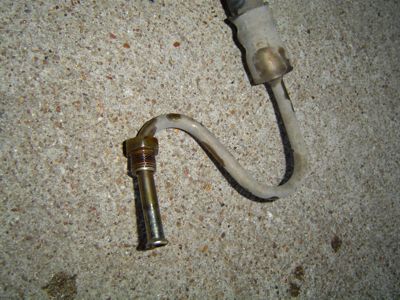 1995 Ford Bronco - A power steering hose with metal fittings lies on a concrete surface.