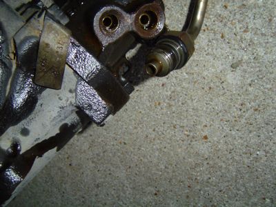 1995 Ford Bronco - This image shows a close-up of a steering gear box part, likely from a vehicle, with visible grease and metal tubing.
