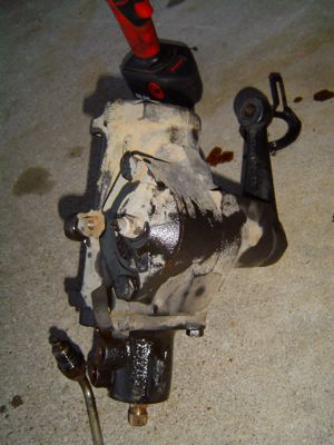 1995 Ford Bronco - Steering gear box removed from a vehicle, with a power tool positioned above it.