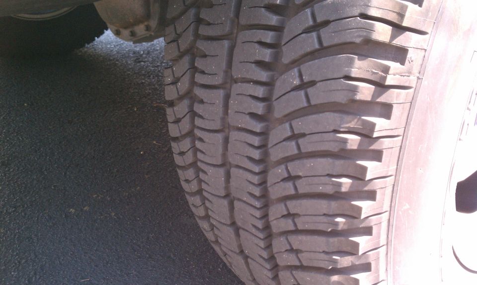 Close-up of a tire tread with visible wear, part of a vehicle's wheel well visible
