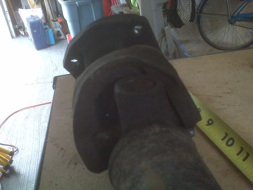 Close-up of a driveshaft U-joint and yoke with a yellow measuring tape showing inches 9, 10, and 11