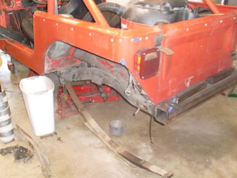 1985 Jeep CJ7 - Rear section of a red 1985 Jeep CJ7 undergoing repairs, with suspension parts visible.