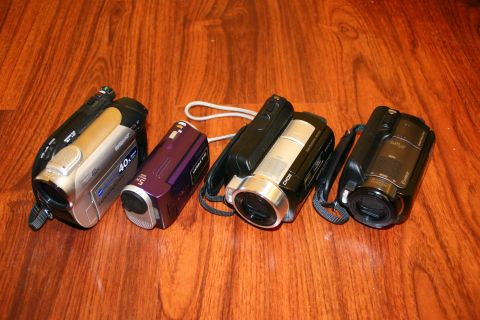 1993 Ford Taurus - A collection of four camcorders is displayed on a polished wooden surface.