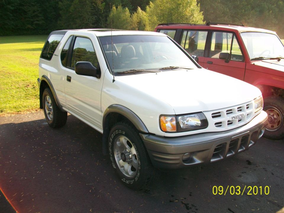 White Isuzu Rodeo parked next to a red SUV. Date stamp says 09/03/2010